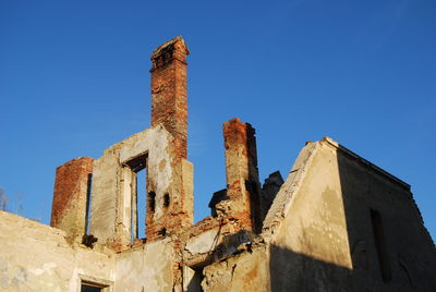 Low angle view of damaged building against clear blue sky