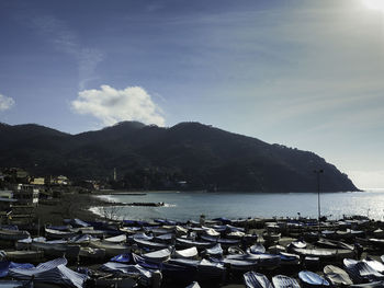 Sailboats moored at harbor by mountains against sky