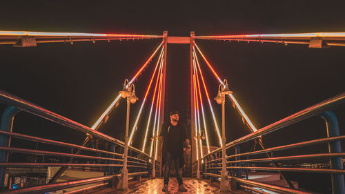 Low angle view of illuminated suspension bridge against sky at night