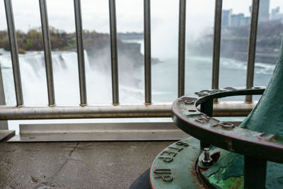 Close-up of railing by river against sky