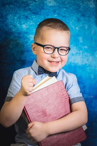 Portrait of smiling boy holding eyeglasses