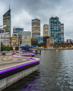 View of swimming pool by river against buildings in city