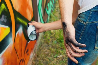 Dirty hand of artist painting graffiti on wall