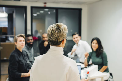 Businesswoman discussing with colleagues in board room at office