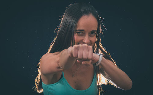 Portrait of smiling mid adult woman punching against black background