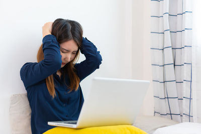 Side view of young woman using digital tablet while sitting at home