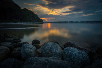 Rocks at sea shore against sky during sunset