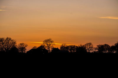 Silhouette trees against dramatic sky during sunset