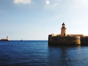 Lighthouse by sea against sky