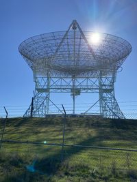 Low angle view of communications tower on field against sky