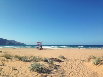 Scenic view of beach against clear blue sky