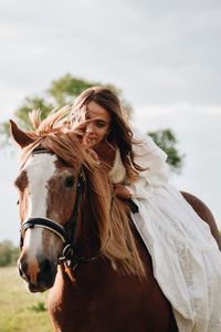 Woman sitting on horse against sky