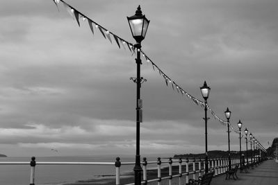 Low angle view of street lights by pier against sky