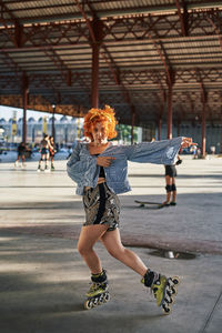 Young alternative redhead dancing in roller skates inside a hangar