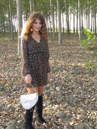 Portrait of smiling young woman standing on land in forest