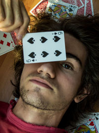 High angle view of man with playing cards lying on hardwood floor