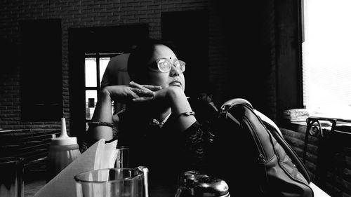 Mid adult woman looking away while sitting at table in restaurant