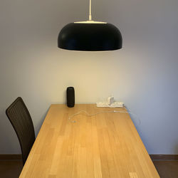 Illuminated pendant light over tables against wall 