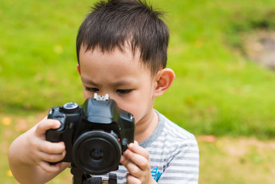 Cute boy photographing while standing at park