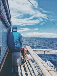Rear view of man sitting on boat in sea
