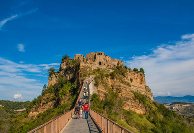 People on mountain road against cloudy sky