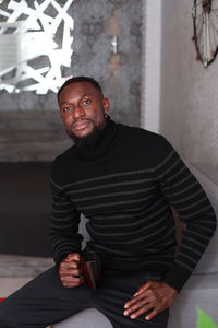 Portrait of young man standing against wall