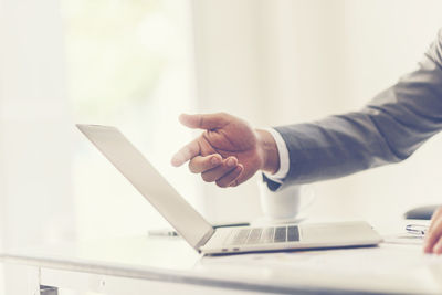 Midsection of man using laptop on table