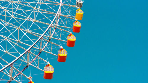 Low angle view of ferris wheel against clear blue sky