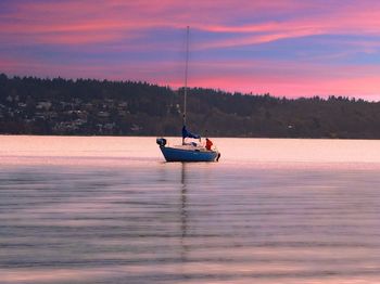 Sailboat sailing on lake against sky during sunset