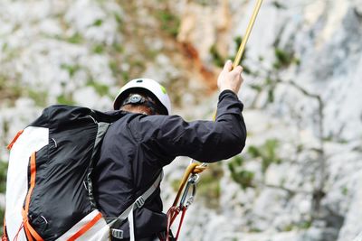 Man with backpack rappelling on mountain