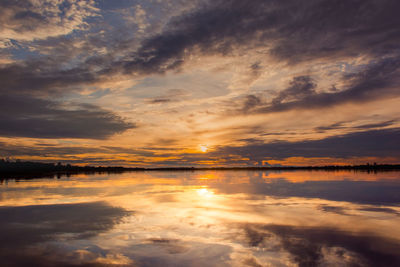 Scenic view of lake against dramatic sky during sunset