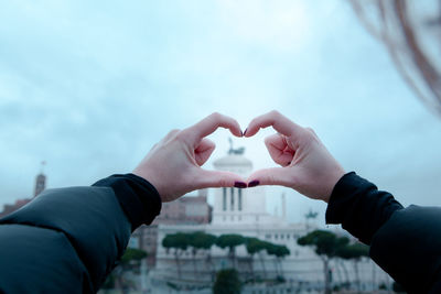 Close-up of hands holding heart shape against sky