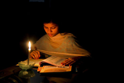 Woman studying with open book in darkroom