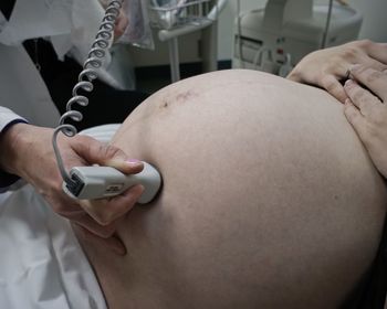 Midsection of doctor examining pregnant woman in hospital