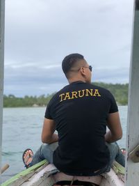 Rear view of man sitting against sky