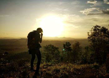 Man standing on field against sky during sunset