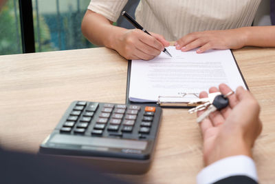 Midsection of man holding paper with text on table