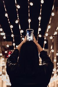 Rear view of woman photographing at night