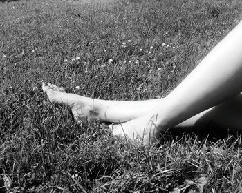 Low section of woman resting on grassy field