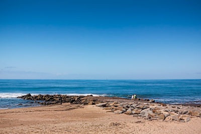 Scenic view of beach and sea against blue sky