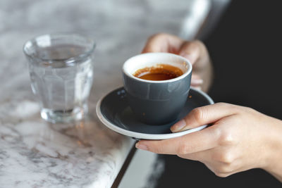 Midsection of man holding coffee on table