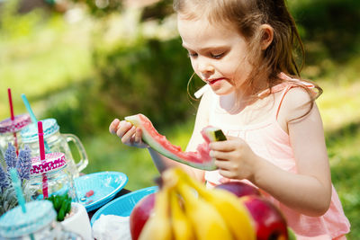 Cute girl eating watermelon in yard