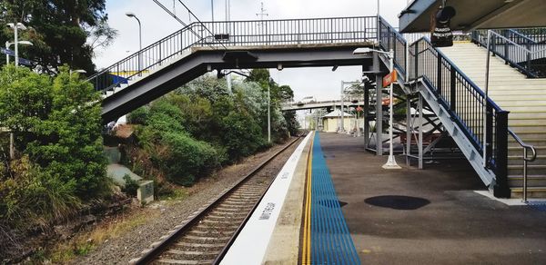 Railroad tracks by bridge against sky