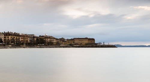 Sea by cityscape against sky