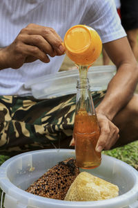 Midsection of man pouring honey