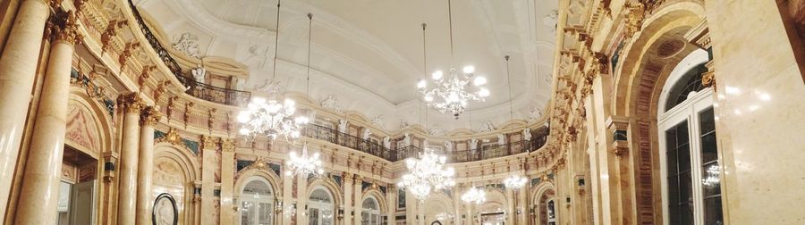 Low angle view of illuminated lights hanging on ceiling of building