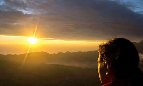 Rear view of woman against sky during sunset