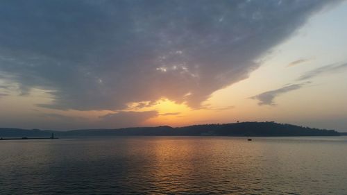 Scenic view of sea against cloudy sky at sunset