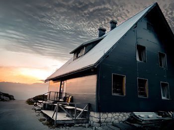 House by sea against sky during sunset