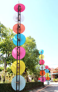 Low angle view of multi colored umbrellas hanging against sky